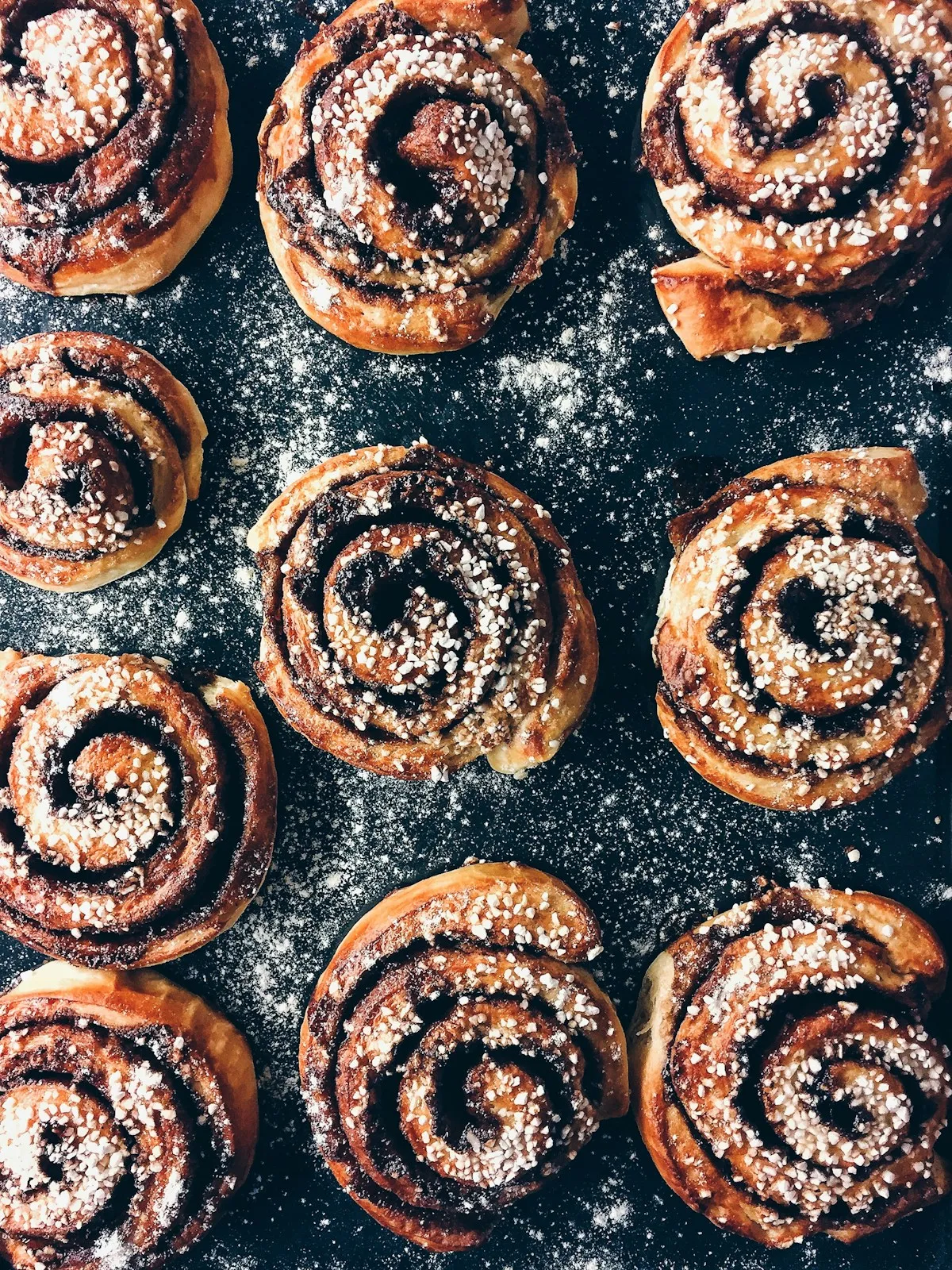 Frisch gebackene Zimtschnecken mit Puderzucker, Draufsicht.