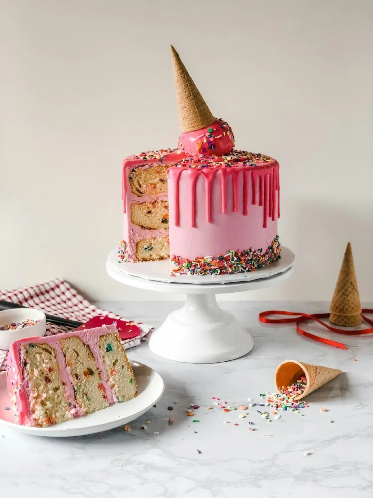 Schokoladentorte mit Tropfglasur und Cremetuffs auf einer Kuchenplatte.